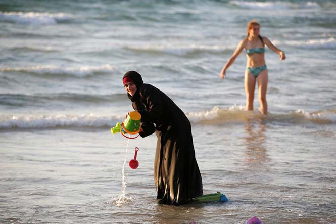 Μία Μουσουλμάνα που φοράει Hijab κοντά στη θάλασσα καθώς μία Ισραηλινή στέκεται κοντά, σε μία παραλία του Tel Aviv, στο Ισραήλ. 21 Αυγούστου 2016. REUTERS/Baz Ratner 