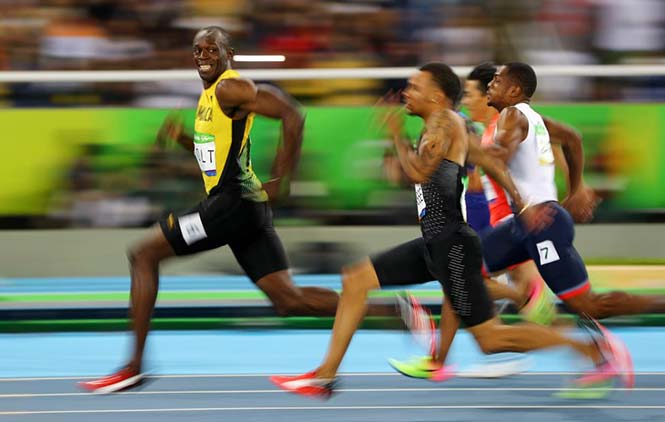Ο Usain Bolt της Τζαμάικα κοιτάει τον Andre De Grasse του Καναδά καθως αγωνίζονται στους ημιτελικούς των 100 μέτρων στους Ολυμπιακούς Αγώνες του Ρίο, στις 14 Αυγούστου 2016. REUTERS/Kai Pfaffenbach 