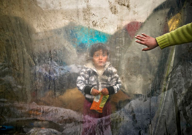 Ένα παιδάκι πίσω από ένα πλαστικό κάλυμμα στην Ειδομένη, 15 Μαρτίου 2016. Vadim Ghirda—AP 