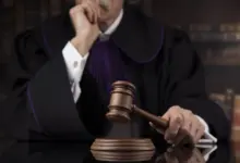 Δικαστής κρατά σφυρί δικαστηρίου, σύμβολο δικαιοσύνης και νομικών αποφάσεων