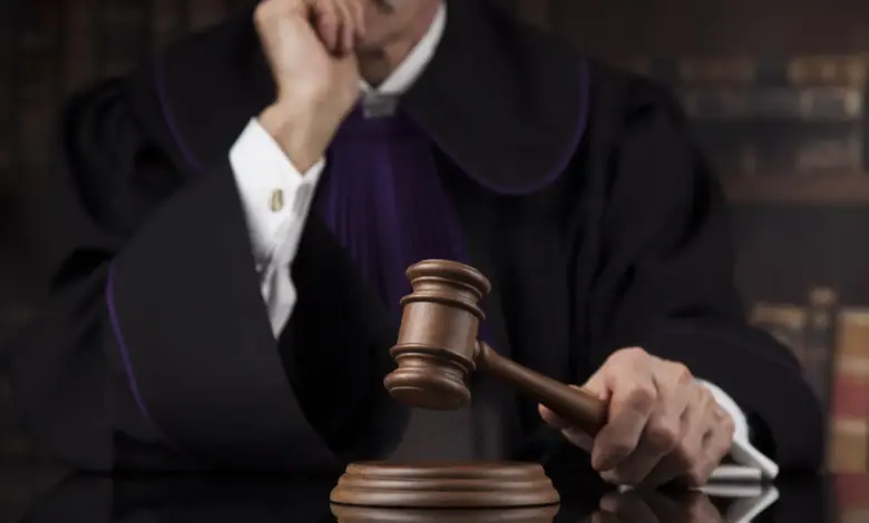 Δικαστής κρατά σφυρί δικαστηρίου, σύμβολο δικαιοσύνης και νομικών αποφάσεων