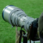 Φωτογράφος κρατά επαγγελματική κάμερα σε αθλητική φωτογράφιση, με έμφαση στον φακό