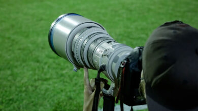 Φωτογράφος κρατά επαγγελματική κάμερα σε αθλητική φωτογράφιση, με έμφαση στον φακό