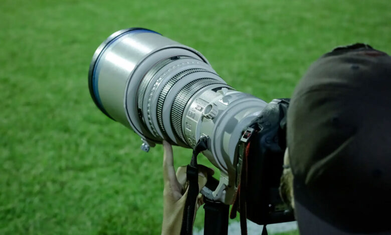 Φωτογράφος κρατά επαγγελματική κάμερα σε αθλητική φωτογράφιση, με έμφαση στον φακό