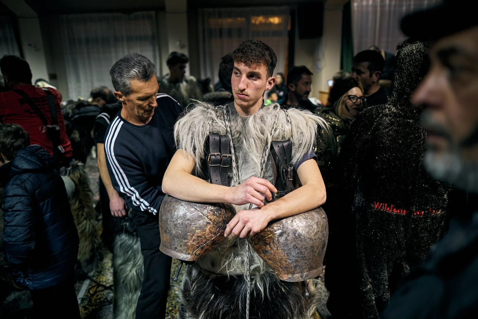 Young participant wearing animal skins and large bells before the event