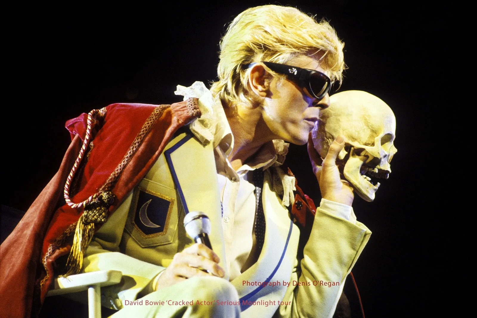 David Bowie wearing sunglasses and holding a skull while performing Cracked Actor in 1983