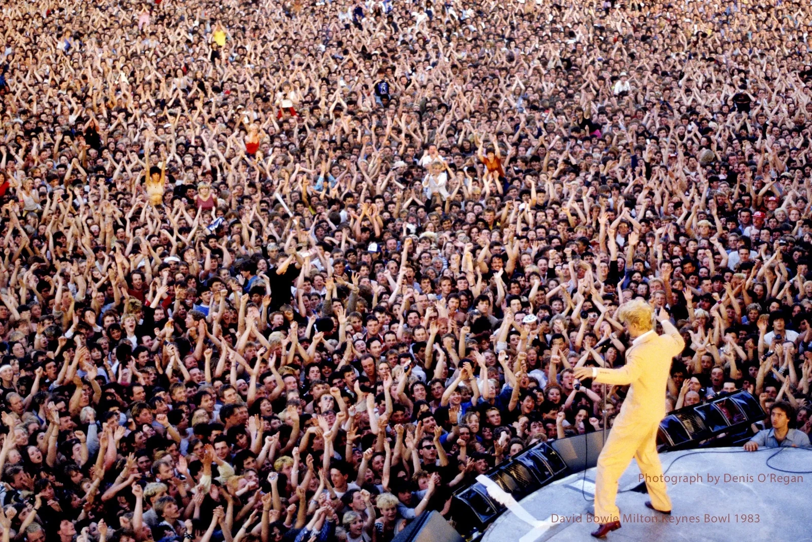 David Bowie in a yellow suit on stage at Milton Keynes Bowl before a large crowd in 1983