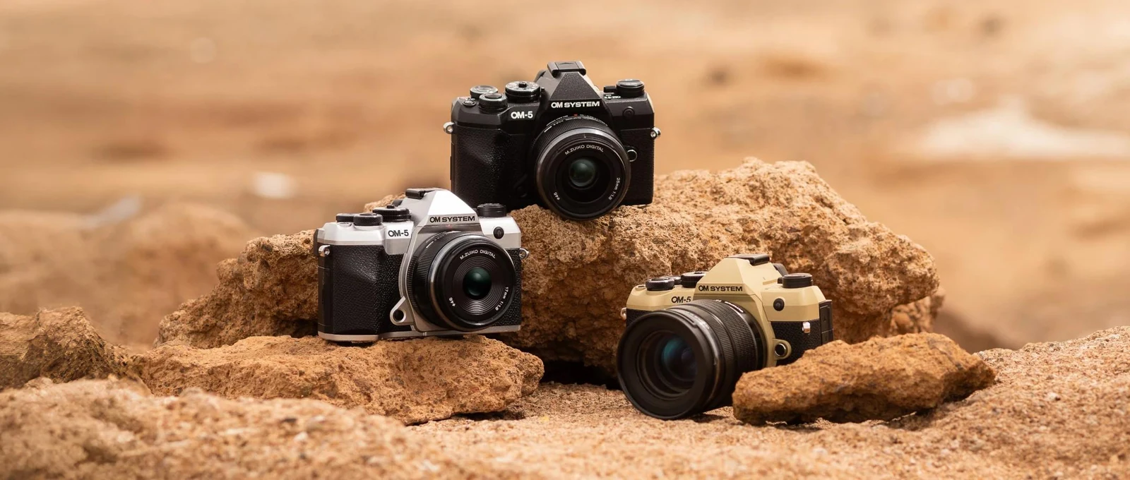 Οι τρεις χρωματικές εκδόσεις της OM System OM-5 Mark II πάνω σε βράχια