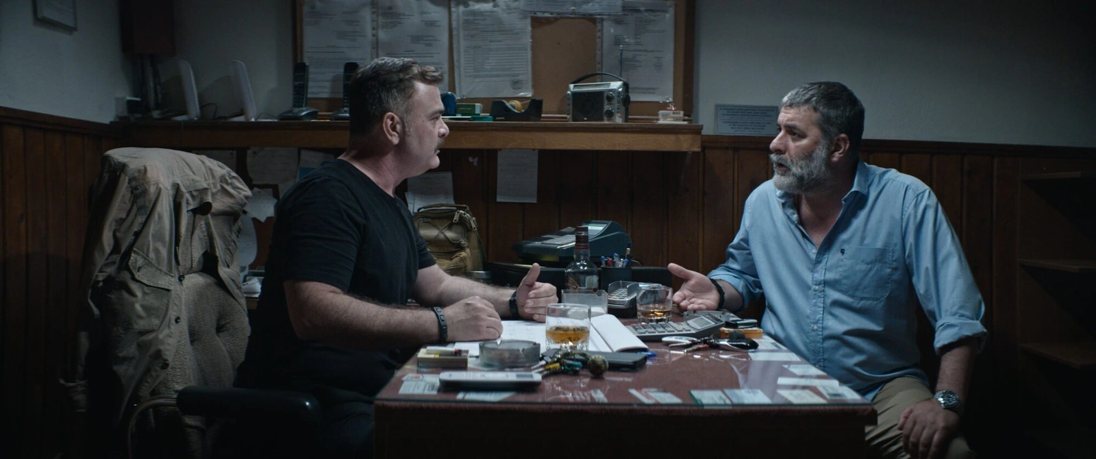 Two men talking across a crowded office desk