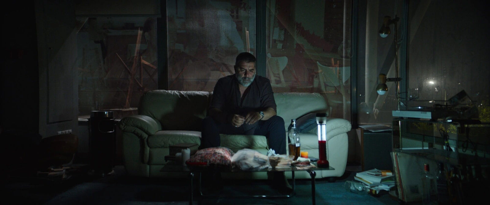 The main character sitting on a sofa in a dark living room