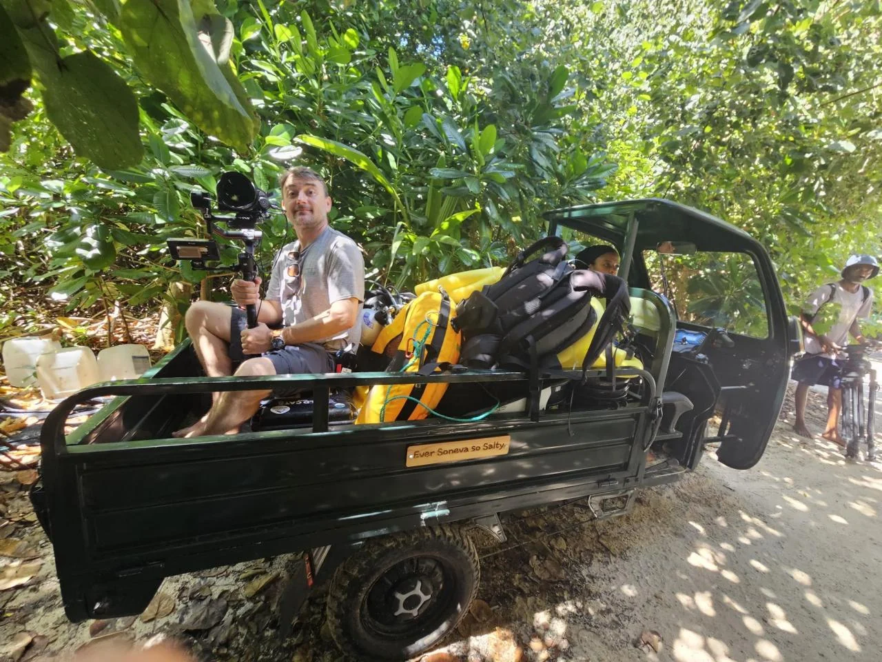 Κινηματογραφιστής με camera rig και εξοπλισμό πάνω σε μικρό όχημα σε τροπικό περιβάλλον