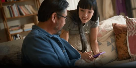 A father and teenage daughter look at a smartphone in an official Uber Teen Accounts image