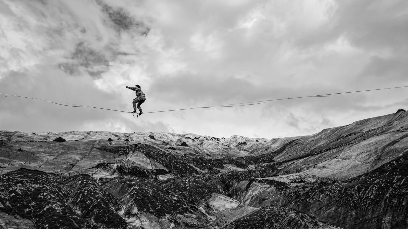 Athlete on a highline above Sólheimajökull glacier under a cloudy sky