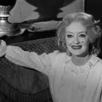 Η Bette Davis καθισμένη σε σκηνή από την ασπρόμαυρη ταινία «Τι Απέγινε η Μπέιμπι Τζέιν;»