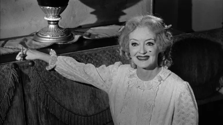 Η Bette Davis καθισμένη σε σκηνή από την ασπρόμαυρη ταινία «Τι Απέγινε η Μπέιμπι Τζέιν;»