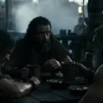 Σκηνή από την AI Οδύσσεια του Grok: τρεις άνδρες γύρω από ένα ξύλινο τραπέζι σε σκοτεινό σκηνικό πλοίου