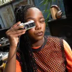 Γυναίκα κρατά τη μικροσκοπική Fujifilm instax Pal 2 μπροστά στο πρόσωπό της