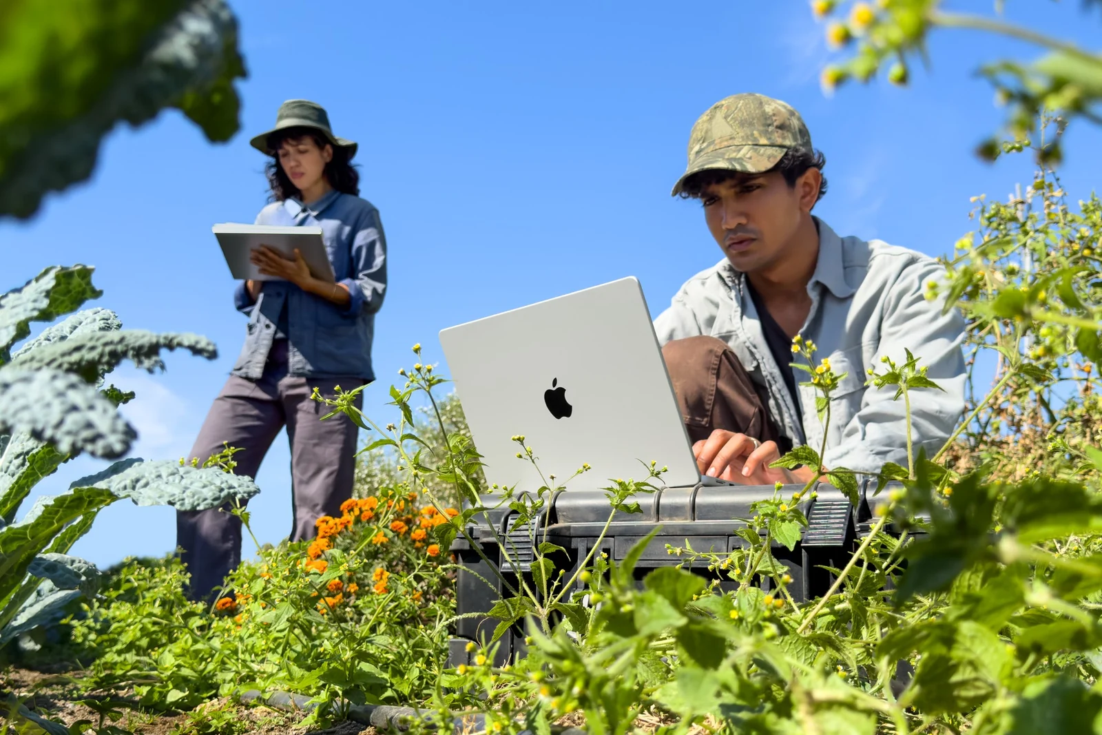 Two creators working outdoors with a MacBook Pro