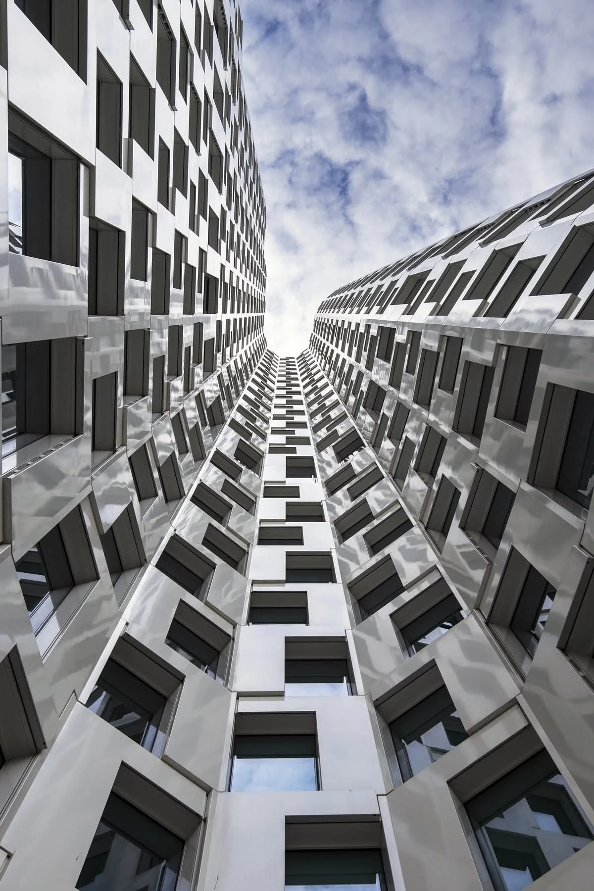 Upward-looking photograph between modern building facades with repeating geometric patterns