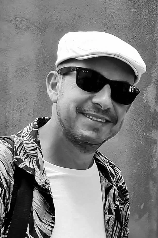 Black-and-white portrait of photographer Mehmet Yasa wearing a cap and sunglasses