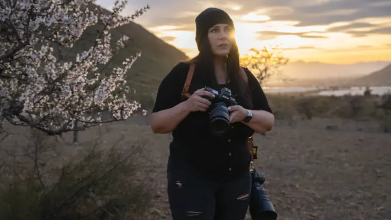 Φωτογράφος με Nikon φωτογραφική μηχανή και τηλεφακό σε εξωτερικό τοπίο κατά το ηλιοβασίλεμα