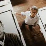 Ο Richard Avedon στέκεται ανάμεσα σε δύο μεγάλες φωτογραφικές εκτυπώσεις και κοιτάζει προς την κάμερα