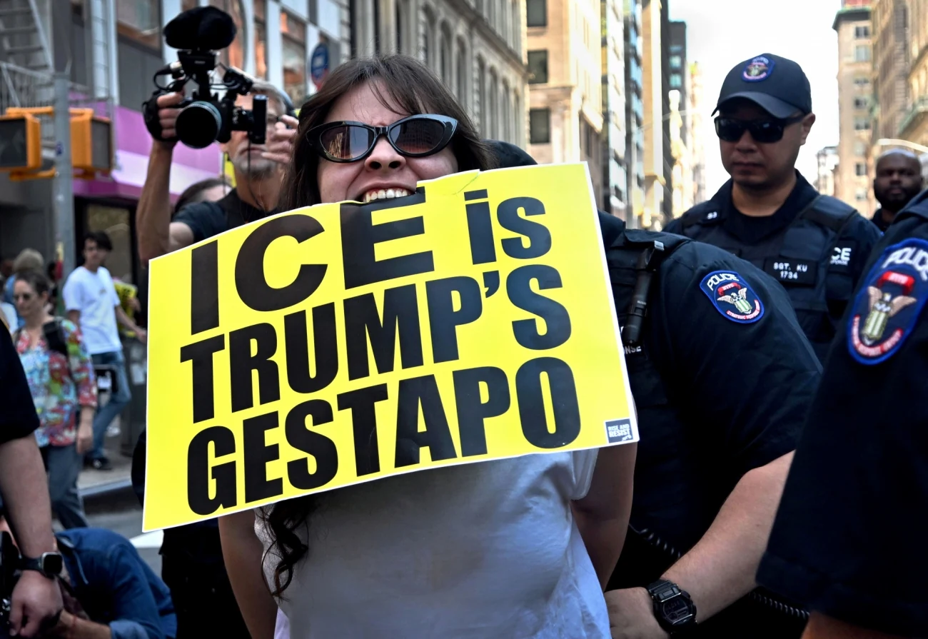 Διαδηλώτρια με πλακάτ κατά της ICE δίπλα σε αστυνομικούς